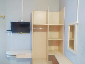 Cette chambre dispose d'étagères blanches et d'une télévision. dans l'établissement RedDoorz at DeAmartaLoka Colomadu Solo, à Colomadu