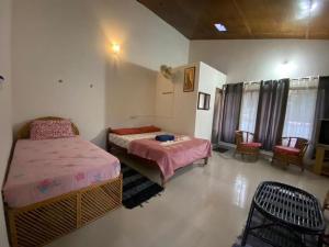 1 dormitorio con 2 camas, mesa y sillas en Coorg Sai Estate Ecobreeze Homestay, en Madikeri