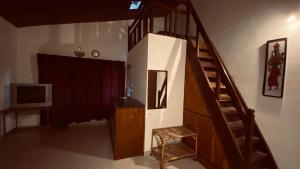 a living room with a staircase and a television at Coorg Sai Estate Ecobreeze Homestay in Madikeri