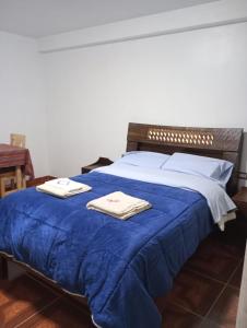 Una cama azul con dos toallas encima. en HOTEL SÚMAQ PUÑUY, en Yungay