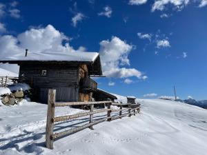 an old cabin in the snow with a fence at Mountain Stay Unterkircher in Terento