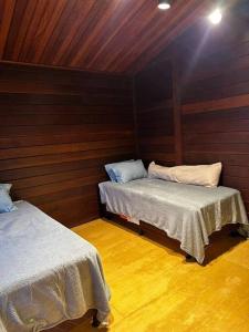 two beds in a room with wooden walls at Casa Monte Verde in Petrópolis
