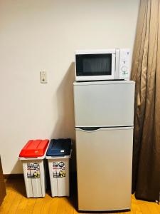 a microwave on top of a refrigerator with two trash cans at Yuyu House Kohama Teru - Vacation STAY 15334 in Osaka
