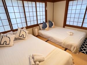 two twin beds in a room with windows at Yuyu House Kohama Teru - Vacation STAY 15334 in Osaka