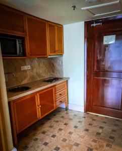 eine Küche mit Holzschränken, einer Spüle und einem Kühlschrank in der Unterkunft Langkawi Lagoon Resort Seaview in Pantai Cenang