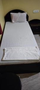 uma cama com lençóis brancos e almofadas num quarto em RK GUEST HOUSE em Bodh Gaya