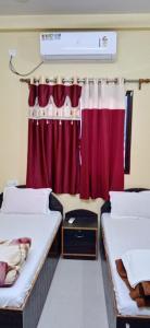 um quarto com duas camas e uma cortina vermelha em RK GUEST HOUSE em Bodh Gaya