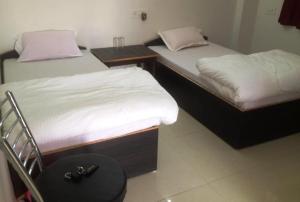 Duas camas individuais num quarto com uma mesa e uma mesa preta em RK GUEST HOUSE em Bodh Gaya