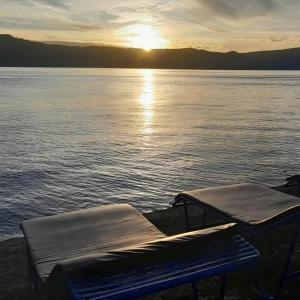 two beds on the shore of a lake at sunset at Hotel Barbara in Tuk Tuk