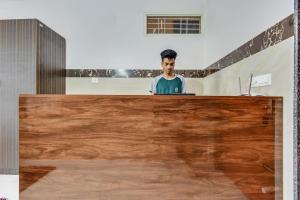 a man sitting at a desk with a laptop at OYO Flagship Sri Sai Guru Comforts in Yelahanka