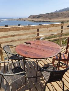 una mesa de madera y sillas en una terraza con la playa en Cabañas la puntilla montaña río y mar, en San Antonio