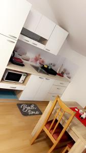 a kitchen with white cabinets and a wooden chair at Apartments and Wellness Ščavničar in Ljutomer