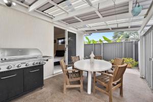 a patio with a table and chairs and a grill at 28 Lorraine Avenue in Marcoola