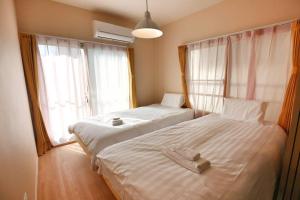 two beds in a room with two windows at Edogawa Japanese Style Apartment 201 has direct access to Akihabara and Shinjuku, with convenient transportation and free WiFi in Tokyo
