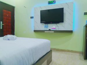 a hotel room with a bed and a flat screen tv at Shiva Home Syariah RedPartner near Alun Alun Tegal in Tegal