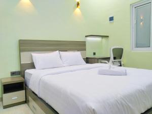 a bedroom with a large white bed and a chair at Shiva Home Syariah RedPartner near Alun Alun Tegal in Tegal