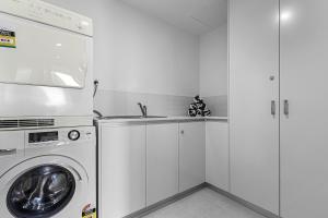 uma cozinha branca com uma máquina de lavar roupa e um lavatório em Peninsula Airlie Beach em Airlie Beach