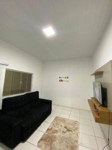 a living room with a black couch and a tv at Casa praia alcobaca 3 quartos in Alcobaça