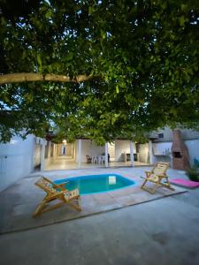 a swimming pool with two chairs and a tree at Casa praia alcobaca 3 quartos in Alcobaça