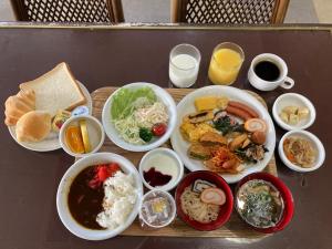 einen Tisch mit Teller mit Lebensmitteln und Schüsseln mit Lebensmitteln in der Unterkunft Hotel Alpha-One Takaoka in Takaoka