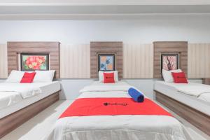 duas camas num quarto com vermelho e branco em RedDoorz Resort Premium @ Sangkan Hurip Kuningan em Kuningan