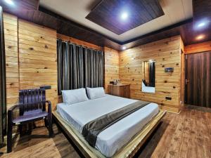 - une chambre avec un lit et un mur en bois dans l'établissement The White Season Residency, à Narkanda