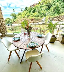 - une table et des chaises en bois sur une terrasse avec vue dans l'établissement Pacific cosy home Bougainvilliers, à Punaauia