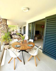 d'une terrasse avec une table en bois et des chaises blanches. dans l'établissement Pacific cosy home Bougainvilliers, à Punaauia