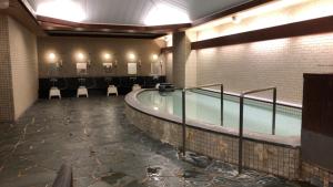a swimming pool in a building with chairs around it at Kanazawa City Hotel in Kanazawa