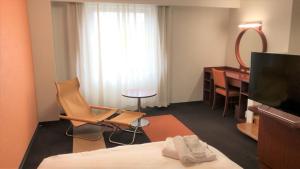 Kanazawa City Hotel في كانازاوا: غرفة في الفندق بها سرير ومكتب ومرآة