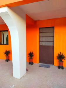 un edificio naranja con una puerta y dos macetas en AUNORA ROOMS with AC, 