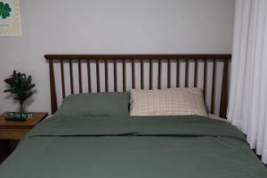 Bett mit einem Kopfteil aus Holz und einem Kissen in der Unterkunft Clover Stay, 2BR,1BA,mapo, free-wifi, in Seoul