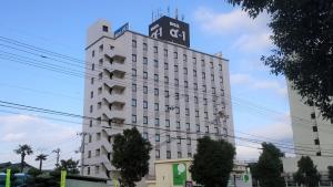 un edificio blanco alto con pájaros encima en Hotel Alpha-One Niihama, en Niihama