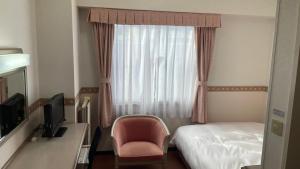 um quarto de hotel com uma cama e uma cadeira e uma janela em Hotel Alpha-One Sabae em Sabae