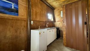 La cuisine est équipée d'un réfrigérateur blanc et d'un évier. dans l'établissement Cabo Polonio - Rancho 66, à Cabo Polonio