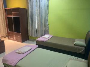 two beds in a room with a green wall at KOTOKOH INN in Machang