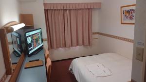 um quarto de hospital com uma cama e uma televisão em Hotel Alpha-One Tsuruga em Tsuruga