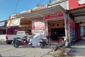 ein Motorrad, das vor einem Gebäude mit Schildern parkt in der Unterkunft OYO 93479 Hotel Jaguar Sentani in Jayapura