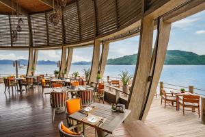 ein Restaurant mit Tischen und Stühlen und Blick auf das Wasser in der Unterkunft An Lam Retreats Ninh Van Bay in Bucht Ninh Van