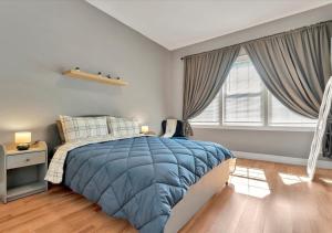 Un dormitorio con una cama con edredón azul y dos ventanas. en The Green Door in Ybor, en Tampa
