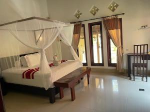 una camera con letto a baldacchino e panca di Teluk Karang Dive & Spa Resort a Tejakula