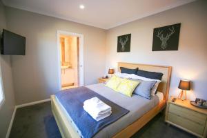 a bedroom with a bed with blue sheets and a television at Amaroo in Bright