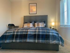 1 cama con manta de cuadros azul y blanco en Glamorous 3 BR Villa with Double Garage, en Regina