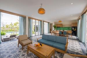 ein Wohnzimmer mit einem blauen Sofa und einem Tisch in der Unterkunft Cocoland River Beach Resort & Spa in Quảng Ngãi
