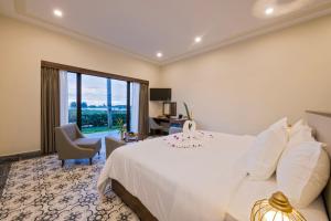 a bedroom with a white bed and a desk and a window at Cocoland River Beach Resort & Spa in Quảng Ngãi