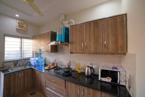 a kitchen with wooden cabinets and a microwave at Grey Orchard Homestay - A Family Place in Lahore