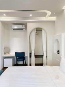 een slaapkamer met een wit bed en een blauwe stoel bij Mellon OASIS Phu Quoc in Phu Quoc