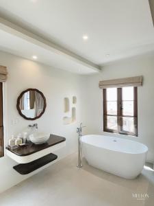 a white bathroom with a large tub and a mirror at Mellon OASIS Phu Quoc in Phu Quoc