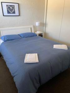 a blue bed with two towels on top of it at Max's Beachside Holiday Home in Torquay