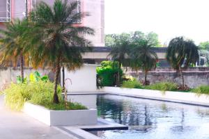 a swimming pool with palm trees in a building at Affordable Condo beside Ayala Mall Bacolod! in Bacolod